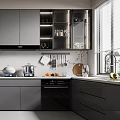 Modern Kitchen With Grey Cabinets Black Appliances Wine Glasses Utensils Fruits Cutting Board And Plant