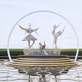 Winged Ballet Dancers Sculpture Under Circular Arch On Golden Base With Reflective Water Green Lawn
