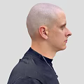 A Bald Head Man in Black Turtleneck Sweater with Silver Necklace Against Light Gray Background