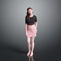 A woman wearing black top and pink skirt against gray background in standing pose