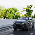 Black SUV Driving on Road with Green Trees and White Guardrail