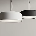 Two Modern White and Black Round Pendant Lights Illuminated Against Gray Wall