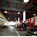 Parking Lot Featuring Red Pipes Hanging Lights Repair Equipment and Parked Cars on Gray Floor