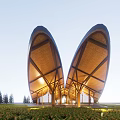 Unique Curved Wooden Facade with Lighting Surrounded by Grass and Trees