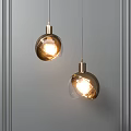 Glowing Modern Pendant Lights With Metallic Base And Transparent Globe Shade On Grey Wall