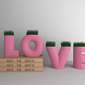 Pink LOVE Letter Shaped Potted Plants With Green Grass And Stacked Arts Crafts Books