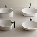 Four White Bathtubs With Different Shapes On Light Colored Tile Floor And Black Faucets