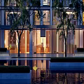 Modern High Rise Residential Building With Glass Facade Balconies And Surrounding Trees Water Feature