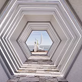 Hexagonal Pergola with Layered Frames and Lighting Overlooking Seaside View Through Stone Pathway
