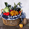 Fresh Assorted Vegetables in Wicker Basket with Blue and White Patterned Cloth on Gray Countertop