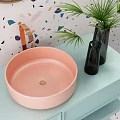 Modern Pink Washbasin on Light Blue Countertop with Brass Faucet Black Vase and Green Plant