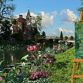 Scenic Garden Landscape Featuring Pond Water Lilies Green Grass Bridge And Red Brick Clock Tower