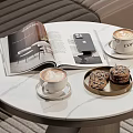 Latte Art Coffee Cups on White Round Marble Table with Open Magazine Phone and Cookies