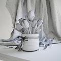 Pink Tulips In Purple Pot With White Ribbon On Gray Fabric Background And Scattered Petals