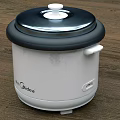 Oster Electric Rice Cooker With White Body And Black Lid On Kitchen Countertop