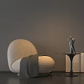 Beige Bean Bag Chair With Gray Blanket Side Table Metal Vase Open Book