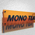 Vibrant Orange Commercial Signage With MONO TEA Lettering Mounted On Wall Surface