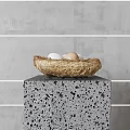 Fresh Eggs in a Straw Nest on a Speckled Gray Stone Pedestal Against Gray Wall