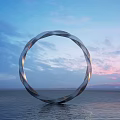 Circular Silver Sculpture Standing On Calm Water Surface Against Blue Sky With Sunset Clouds