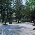 Modern Entrance Gate In Landscaped Area With Trees Benches And Paved Walkway