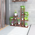 Multi Tiered Wooden Plant Stand With Various Green Plants And Potted Flowers In Balcony Corner
