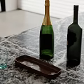 Green Champagne And Dark Wine Bottles On Marble Countertop With Brown Tray And Clear Cup