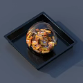 Small Orange And Yellow Wrapped Candies In Transparent Round Container On Black Square Tray
