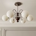 Elegant Chandelier Featuring White Spherical Shades And Dark Brown Balls On Light Wall With Moldings