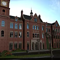 Garden Landscape with Red Brick Building Clock Tower Spire Lamp Posts and Neat Pathways