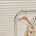 Clothing Hanger with Coats Sweaters Metal Storage Basket in Bedroom Near Window Blinds Green View