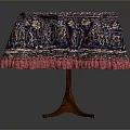 Round Dining Table With Red Blue Patterned Tablecloth And Pink Fringed Edges Wooden Legs