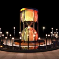 Giant Illuminated Hourglass In Night Scene With Surrounding Light Poles