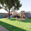 Garden Landscape with Wooden Roof Stone Wall Patio Dining Area Playground and Sunlit Lawn