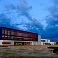 Modern Blue And White Office Building With Large Glass Windows And Parking Area