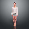 Woman In White Loose Top And Denim Shorts Standing Against Gray Background With Sandals