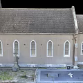 Traditional Church Building With Steeple Tower Brown Exterior Gray Roof Round Window And Arched Doorway