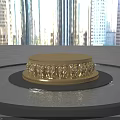 Golden Circular Sculpture Pedestal With Intricate Carved Patterns On Water Surface Against Blue Sky And Gray Floor