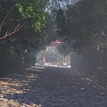 Red Scenic Wall Along Stone Paved Path With Lush Greenery White Statues And Misty Background