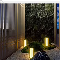 Outdoor Lights Illuminating Garden Pathway With Stone Wall Wooden Slats Greenery And Decorative Rock