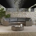 Outdoor Wicker Sofa With Gray Cushions Round Coffee Table And Green Plants By Stone Wall