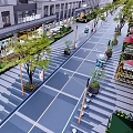 Vibrant Commercial Pedestrian Street With Buildings Greenery Shops Outdoor Seating And Umbrellas