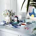 Decorative Ornament Collection with White Daisies Cat Figurine Blue Bowl Notebook and Striped Cloth on Table