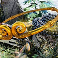 Intricate Golden Spiral Sculpture With Green Plants And Dark Round Fruits