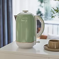 Green Electric Kettle On White Cabinet With Cup And Saucer In Indoor Setting