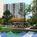Modern Residential Landscape with High Rise Buildings Lush Trees Lawn and Leisure Seating Areas