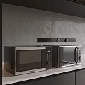 Modern Kitchen With Two Microwaves On Countertop Against Gray Wall And Black Shelf