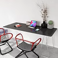 Black Office Desk Against White Wall With Laptop Books Vase Dried Branches Plant Red Chairs