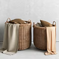 Two Woven Storage Baskets with Brown Beige Pillows and Hanging Blankets Against Gray Wall