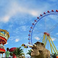 Amusement Park Scene With Ferris Wheel Carousel Dinosaur Model And Balloons Under Blue Sky