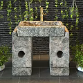 Stone Washbasin With Gold Faucet Against Black Brick Wall Green Vines And Potted Plants